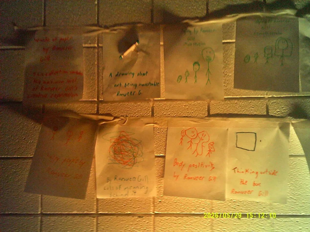 Original artworks by Ranveer Gill pinned to a cinder block wall under selective lighting.